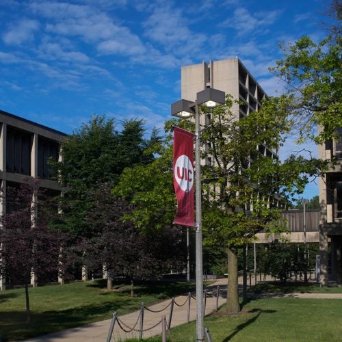 A collection of buildings on East Campus with a light post and UIC banner.