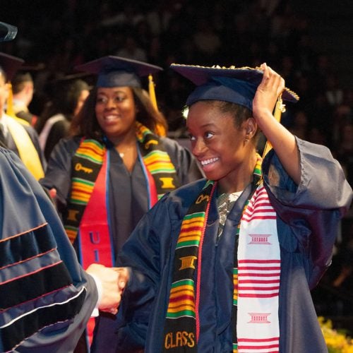 Black students shaking hands with administration at graduation ceremony