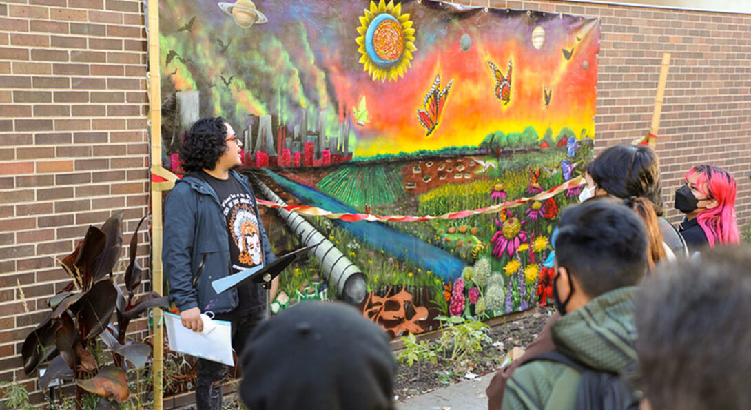 Artist Mario Mena speaks in front of the mural.