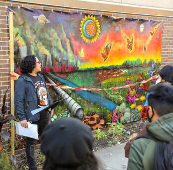 Artist Mario Mena speaks in front of the mural.
                  