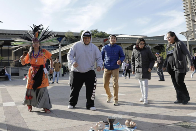 UIC students and staff dance in the quad with an Indigenous dancer.