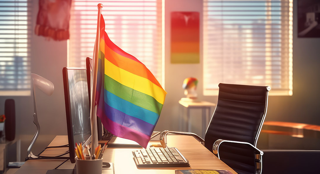 A pride flag standing on a computer desk in an office