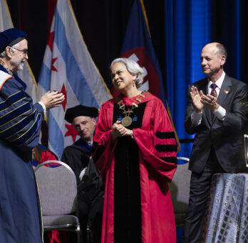 UIC Chancellor receiving applause on stage. 