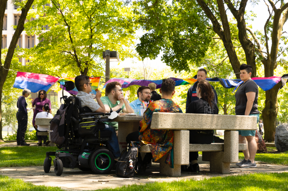 Attendees of the Pride Picnic seated at the grassy patio area behind the Behavioral Sciences Building